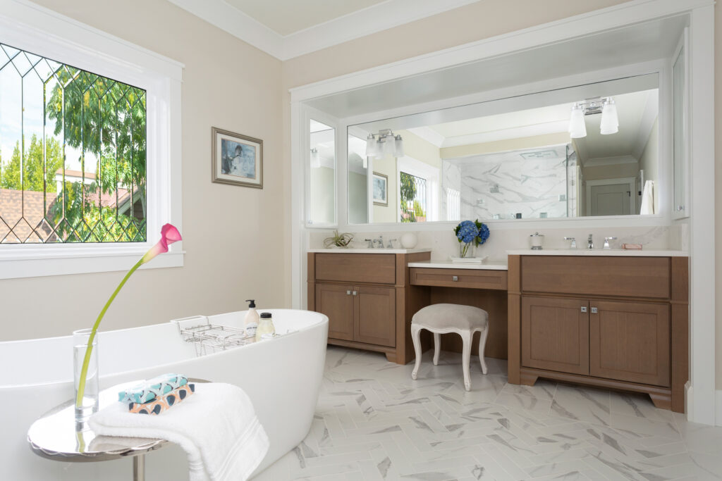 This expansive master bath features cherry wood Omega Cabinetry with a Riverbed stain, furniture style bath vanities, and a free-standing tub by Kohler.  