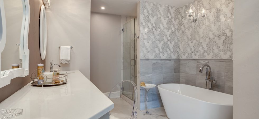 Light grey and white bathroom with soaking tub and chandelier