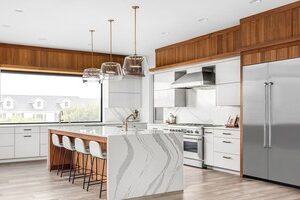 full view of kitchen remodel with large island that doubles as seating area along with wood and white cabinets JM Kitchen & Bath Design