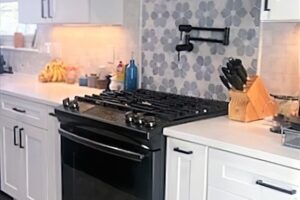 kitchen remodel features gray and white floral tile on wall behind stove JM Kitchen & Bath Design