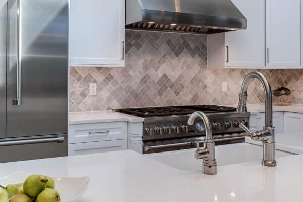 remodeled kitchen features clean, white countertops and large stovetop and oven JM Kitchen & Bath Design