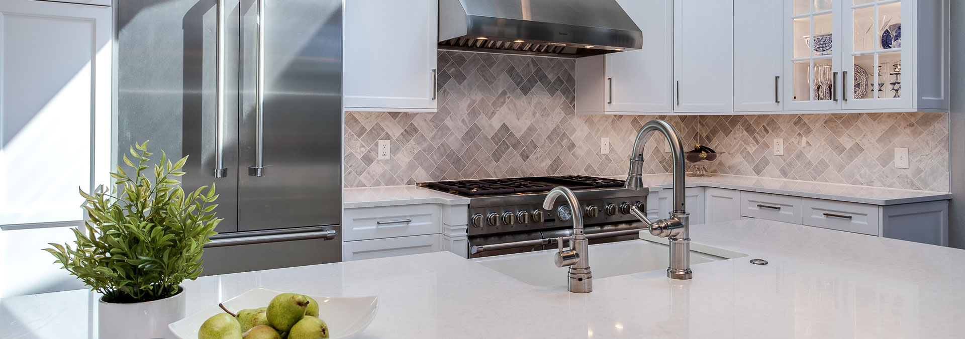 remodeled kitchen features clean, white countertops and large stovetop and oven JM Kitchen & Bath Design