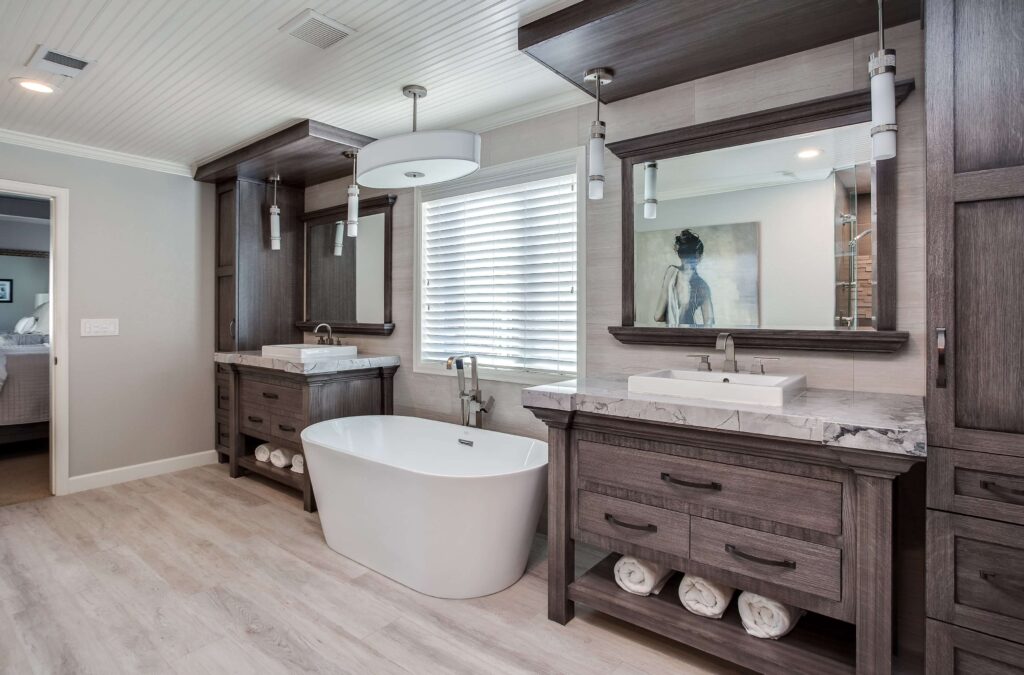 bathroom remodel features separate vanities with raised sinks and free standing tub in the middle in addition to modern lighting JM Kitchen & Bath Design