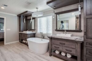 bathroom remodel features separate vanities with raised sinks and free standing tub in the middle in addition to modern lighting JM Kitchen & Bath Design