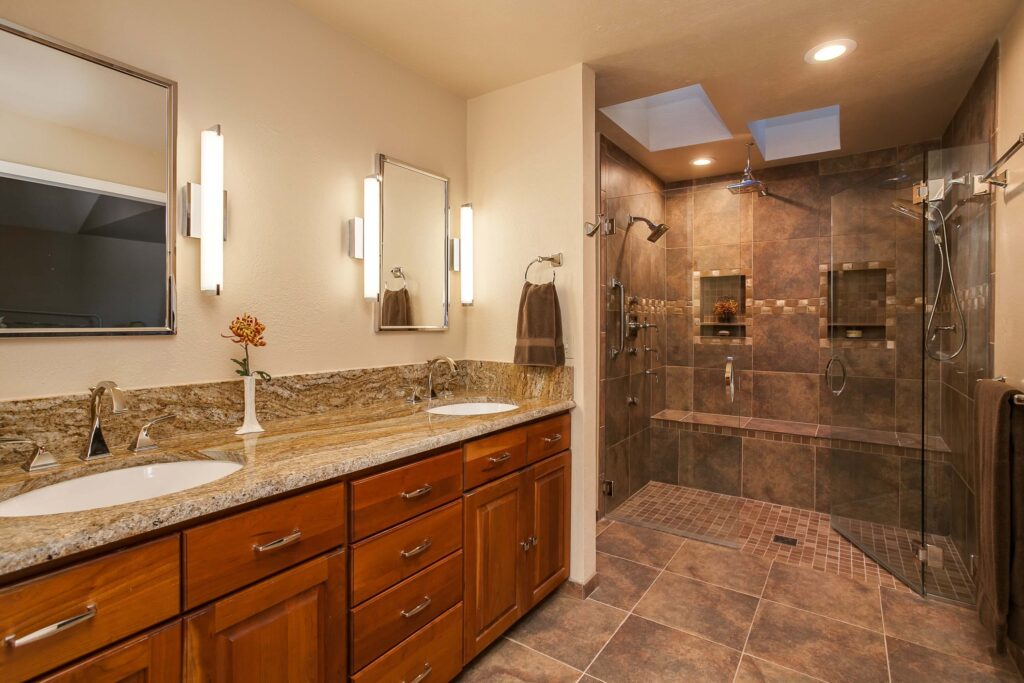 bathroom remodel features double vanity, modern lighting, and large shower with bench JM Kitchen & Bath Design