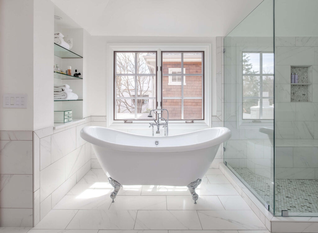 remodeled bathroom from JM Kitchen & Bath Design features large white tub and marble tile