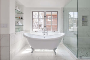 remodeled bathroom from JM Kitchen & Bath Design features large white tub and marble tile