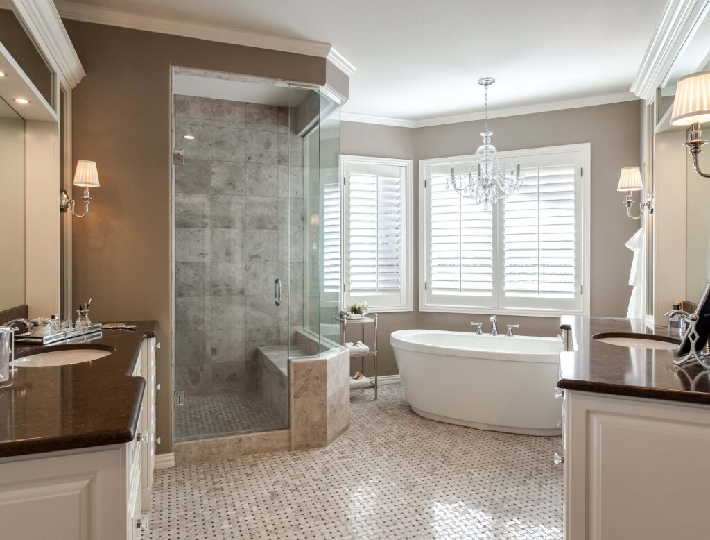 bathroom remodel from JM Kitchen & Bath Design features new tile, two separate vanities and freestanding tub