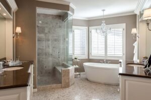 bathroom remodel from JM Kitchen & Bath Design features new tile, two separate vanities and freestanding tub