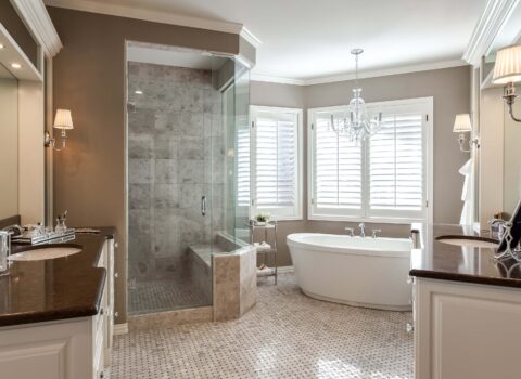 bathroom remodel from JM Kitchen & Bath Design features new tile, two separate vanities and freestanding tub