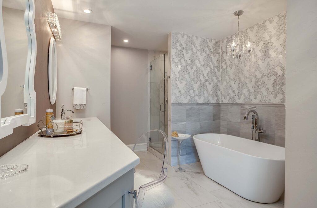 bathroom remodel featuring freestanding tub, gray and white wallpaper, and off white vanity JM Kitchen & Bath Design