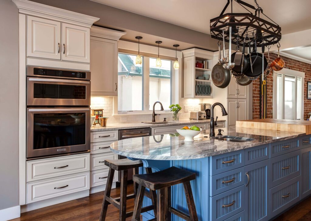 country farmhouse is the theme for kitchen remodel with light blue cabinets under island and pot holder above island JM Kitchen & Bath Design