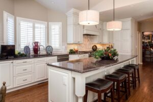 remodeled kitchen with farmhouse feel featuring white cabinets and lighting over island area JM Kitchen & Bath Design