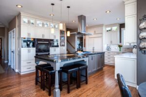 remodeled kitchen featuring gray and white distressed cabinet finishes, island with seating and modern appliances JM Kitchen & Bath Design