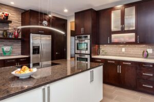 modern kitchen from JM Kitchen & Bath Design features cooktop on island and modern lighting