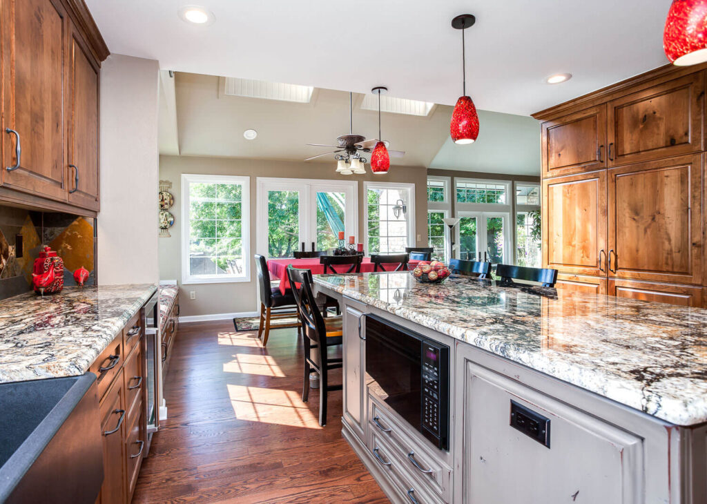 custom kitchen remodel features distressed gray cabinets, low microwave, and granite countertops JM Kitchen & Bath Design