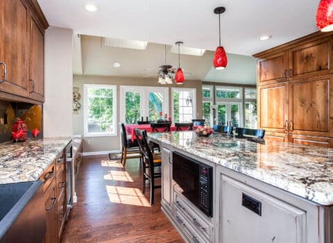 custom kitchen remodel features distressed gray cabinets, low microwave, and granite countertops JM Kitchen & Bath Design