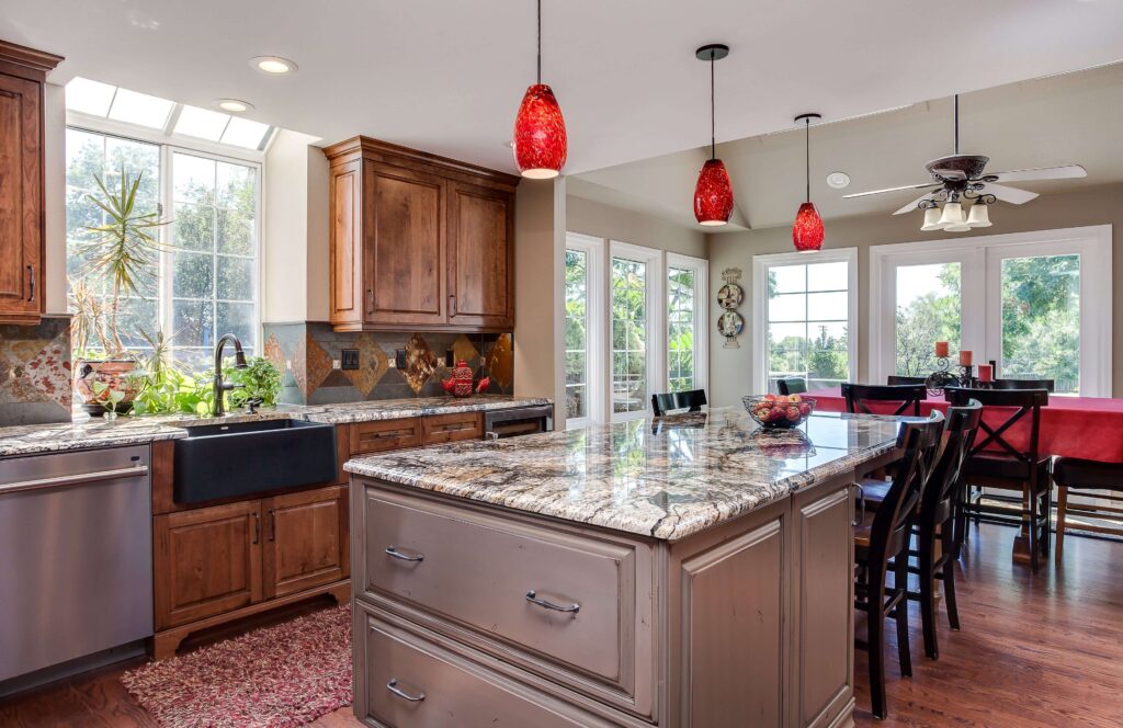 red accent lighting over dual island and seating area with distressed gray cabinets and dark wood cabinets JM Kitchen & Bath Design