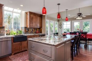 red accent lighting over dual island and seating area with distressed gray cabinets and dark wood cabinets JM Kitchen & Bath Design