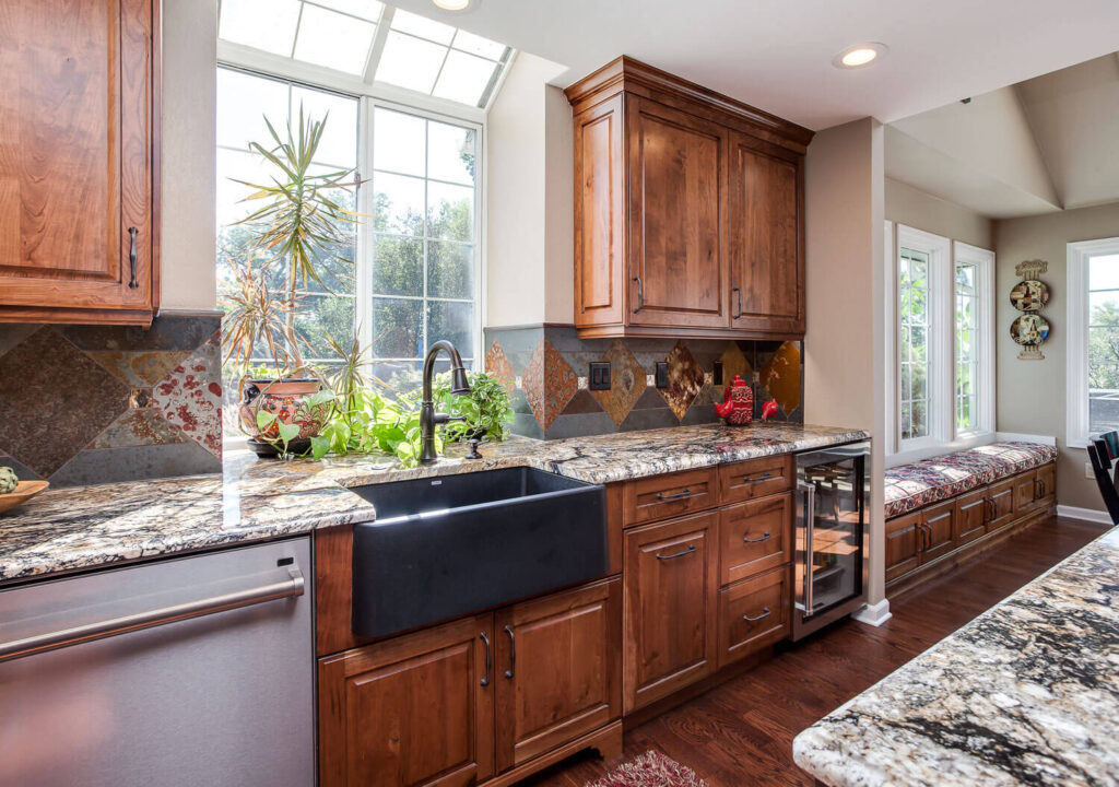 large kitchen and seating area remodel featuring unique copper accents, apron sink, and bench seating area with storage JM Kitchen & Bath Design