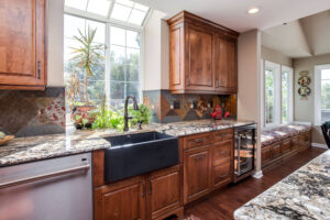 large kitchen and seating area remodel featuring unique copper accents, apron sink, and bench seating area with storage JM Kitchen & Bath Design