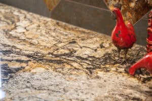 close up of granite countertop in copper, black, and light gray with red hen decor in remodeled kitchen JM Kitchen & Bath Design