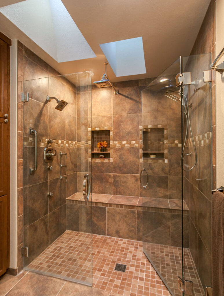 bathroom remodel features two skylights, dual shower heads, large bench, and cove for shampoo, soap, and other essentials JM Kitchen & Bath Design