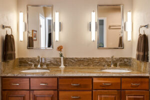 view of double vanity, two mirrors, and modern vertical light fixtures with cabinet space in remodeled bathroom JM Kitchen & Bath Design