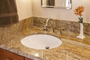 granite countertop and sink with chrome faucet in remodeled bathroom JM Kitchen & Bath Design