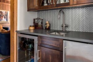 remodeled bar includes dark wood cabinets and tile with filigree design JM Kitchen & Bath Design