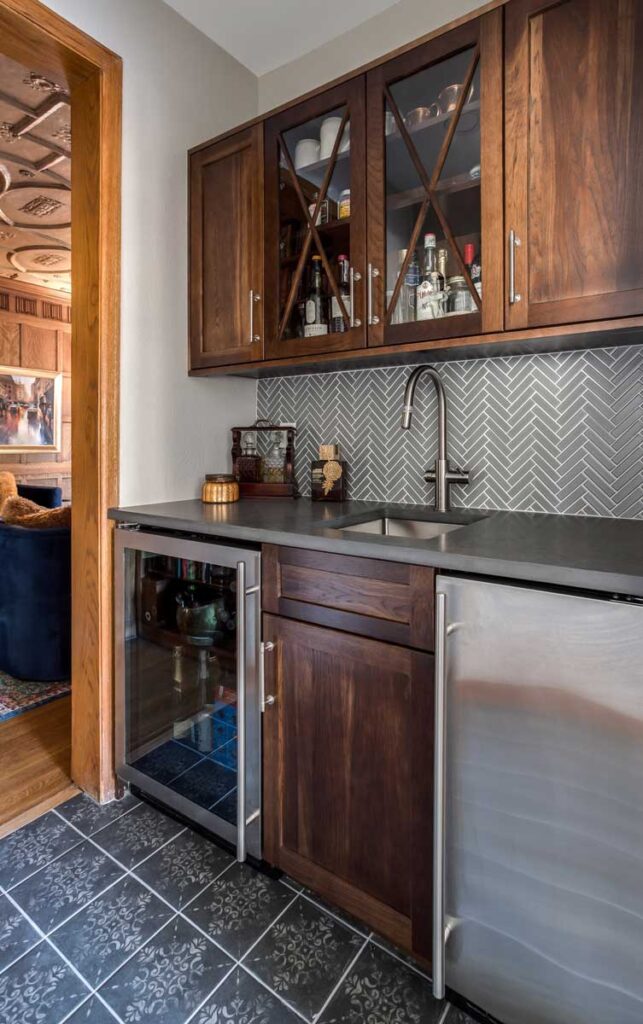 remodeled bar includes dark wood cabinets and tile with filigree design JM Kitchen & Bath Design