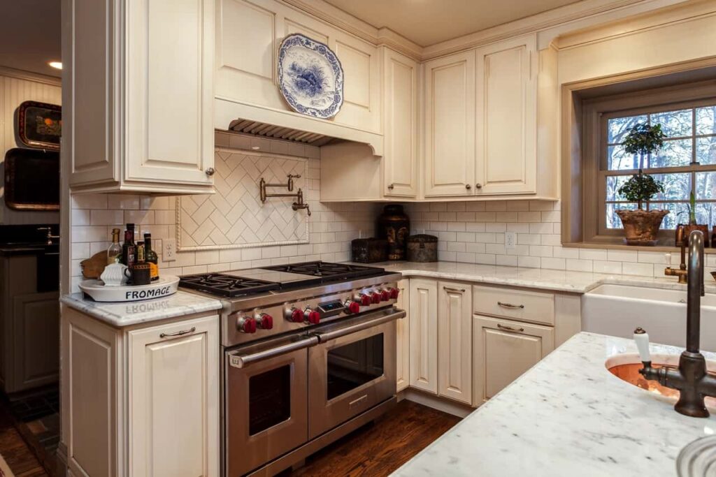 remodeled kitchen with country finishes - apron sink, off white, distressed cabinets and copper accents JM Kitchen & Bath Design