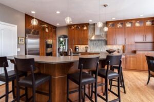 kitchen remodel with modern touches with large bar seating area with tall bar stools, upgraded appliances, and wood cabinets JM Kitchen & Bath Design