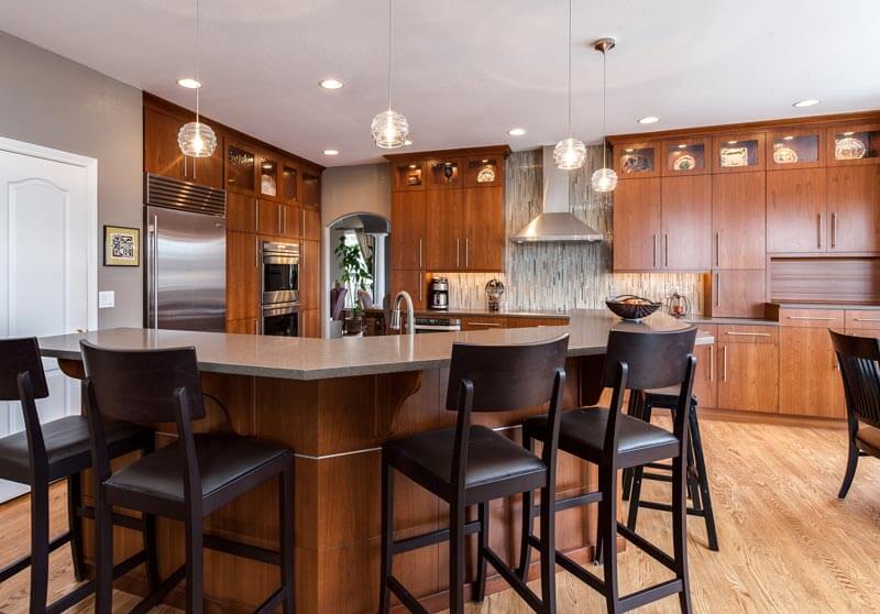 kitchen remodel with modern touches with large bar seating area with tall bar stools, upgraded appliances, and wood cabinets JM Kitchen & Bath Design