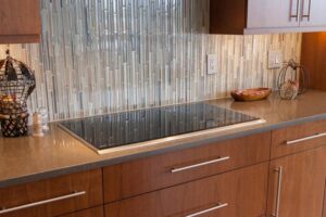 long cabinet hardware, glass backsplash and flat cooktop create a modern look to remodeled kitchen JM Kitchen & Bath Design