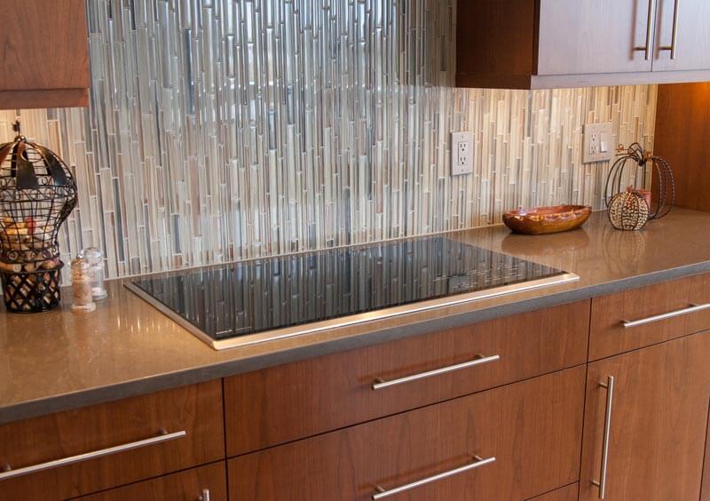 long cabinet hardware, glass backsplash and flat cooktop create a modern look to remodeled kitchen JM Kitchen & Bath Design