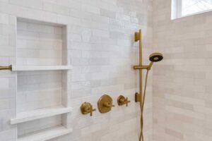 updated shower showcases matte brass finishes and light gray tile JM Kitchen & Bath Design