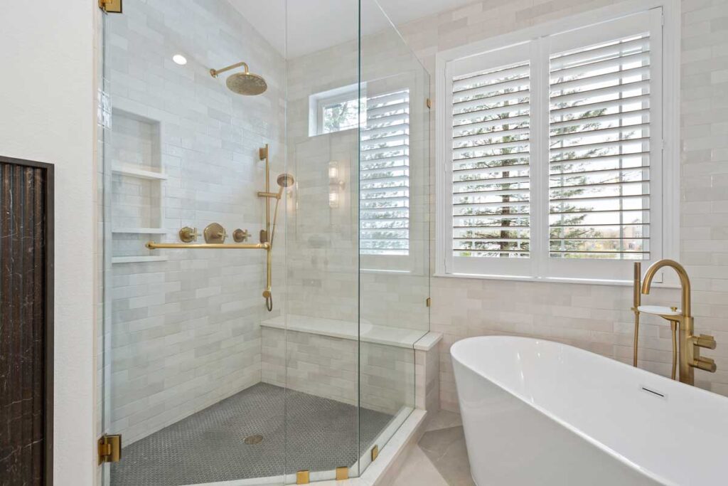 bathroom remodel includes shower with glass door, light gray tile, and matte brass hardware JM Kitchen & Bath Design