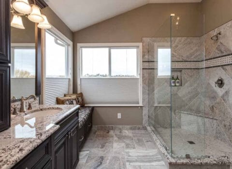 JM Kitchen & Bath Design bathroom remodel features walk-in shower with bench, sitting area, privacy blinds and plenty of storage