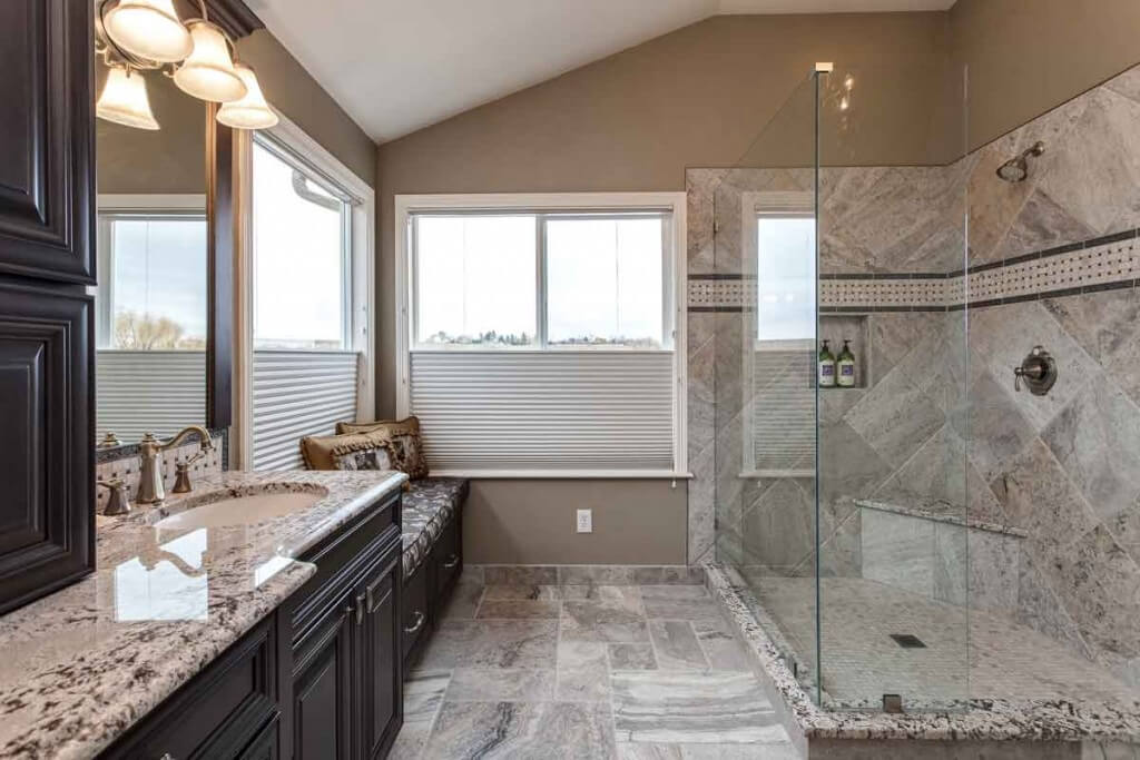 JM Kitchen & Bath Design bathroom remodel features walk-in shower with bench, sitting area, privacy blinds and plenty of storage