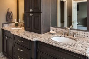 dark gray cabinetry finish and dual vanity with gray accents are features in remodeled bathroom by JM Kitchen & Bath Design