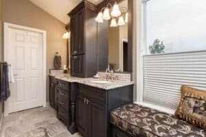 remodeled bathroom by JM Kitchen & Bath Design features dark wood cabinetry double vanity and sitting area