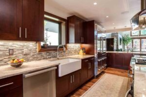 remodeled kitchen from JM Kitchen & Bath Design features apron sink, large refrigerator, and beautiful countertops