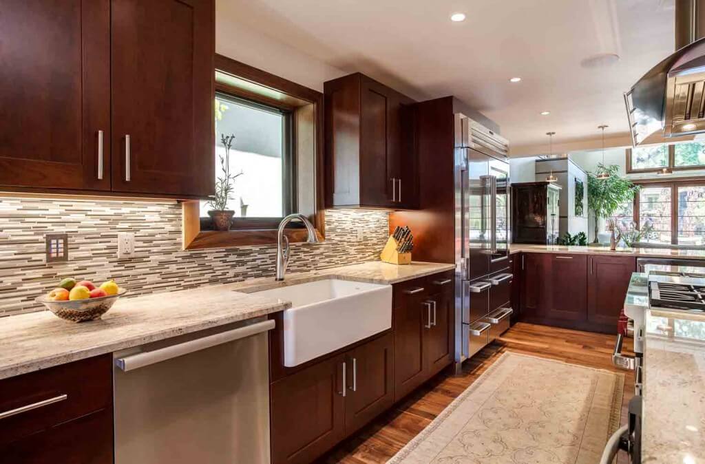 remodeled kitchen from JM Kitchen & Bath Design features apron sink, large refrigerator, and beautiful countertops