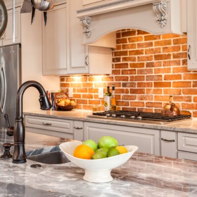 Kitchen with marble countertop island and brick backsplash JM Kitchen & Bath Design