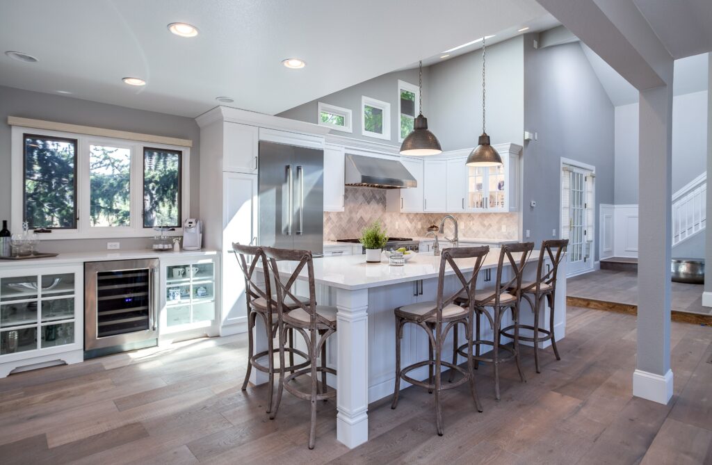 White painted kitchen cabinets with stainless steel appliances with ambient, task and ambiance lighting.