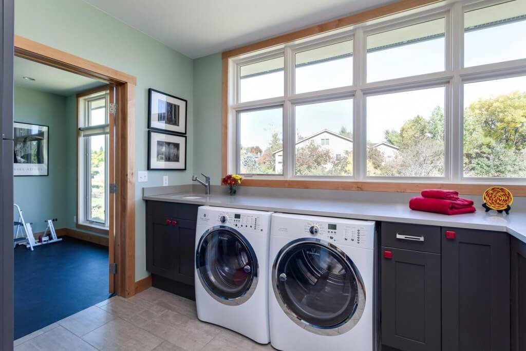 updated, remodeled laundry room with natural light from large windows, modern appliances, sink, and a lot of counter space