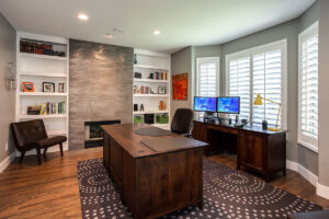 home study remodel with modern finishes on fireplace wall, white shutters, and dark wood desks JM Kitchen & Bath Design