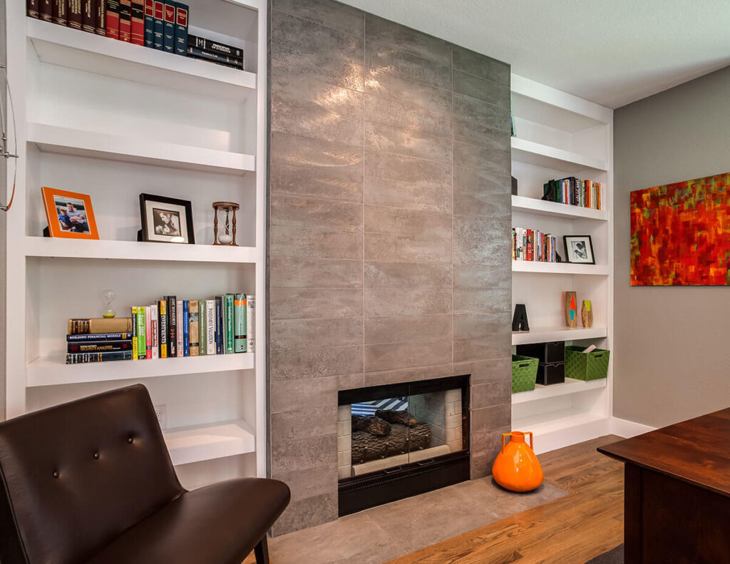 modern home office remodel showcasing small fireplace with unique wall finish and book shelves on either side JM Kitchen & Bath Design