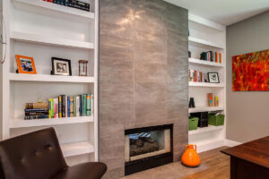 modern home office remodel showcasing small fireplace with unique wall finish and book shelves on either side JM Kitchen & Bath Design